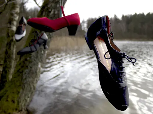 Red and black designer shoes by a snowy lake